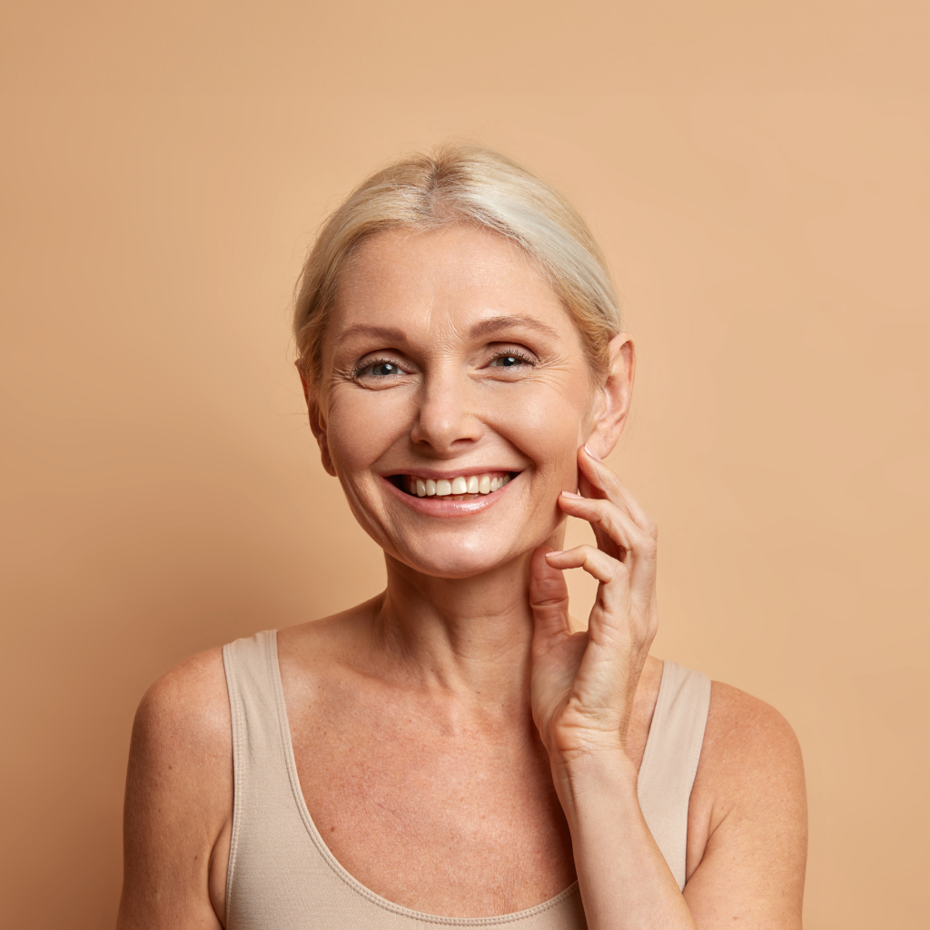 women with grey blond hair smiling against a cream background with visible smile lines