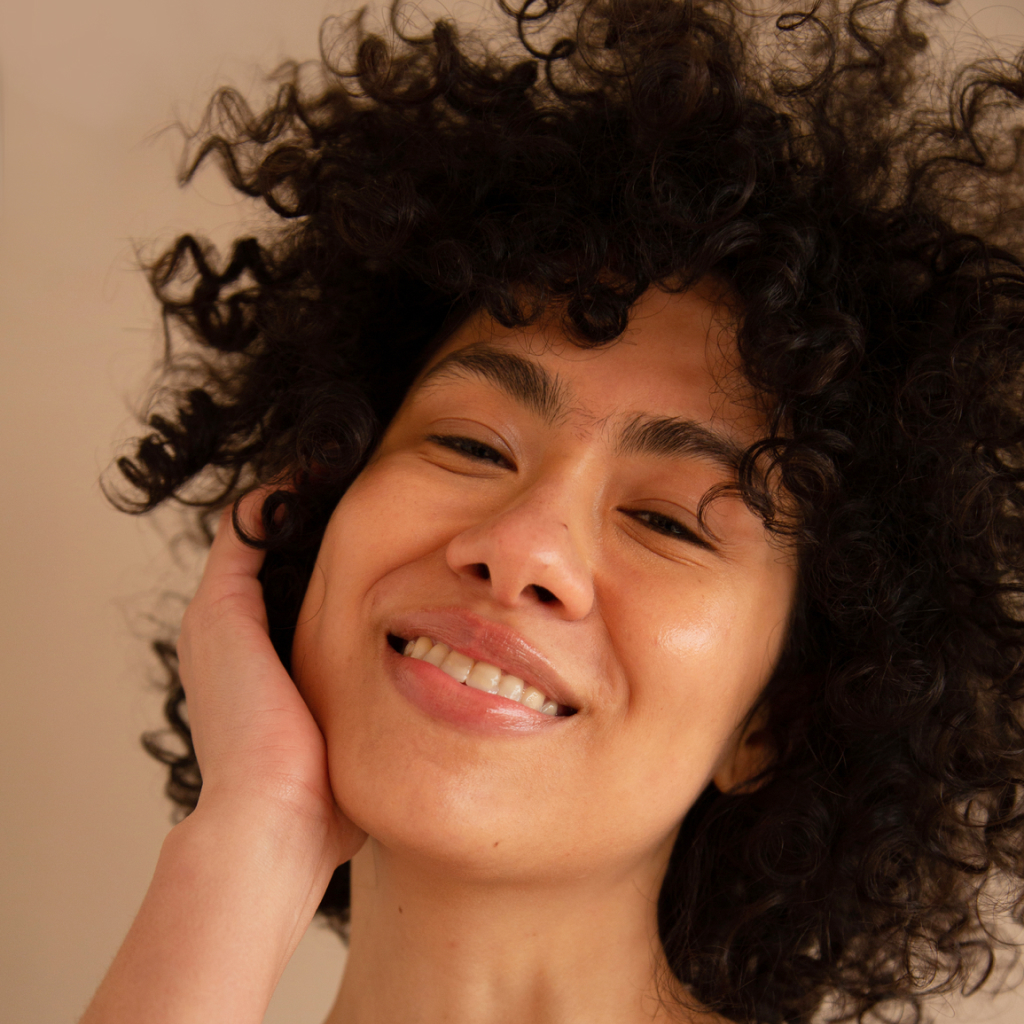 asian women with dark curly smiling on a beige background