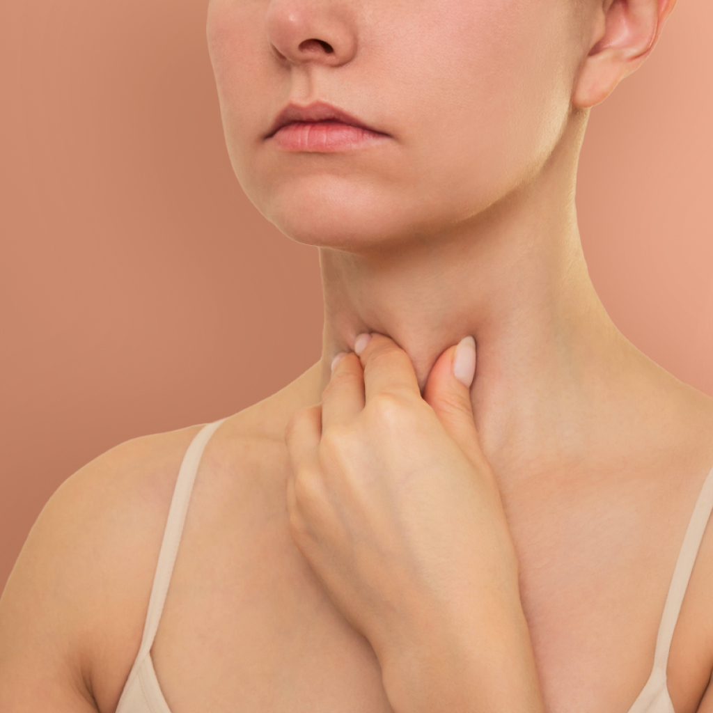 women caressing her throat on a blush background
