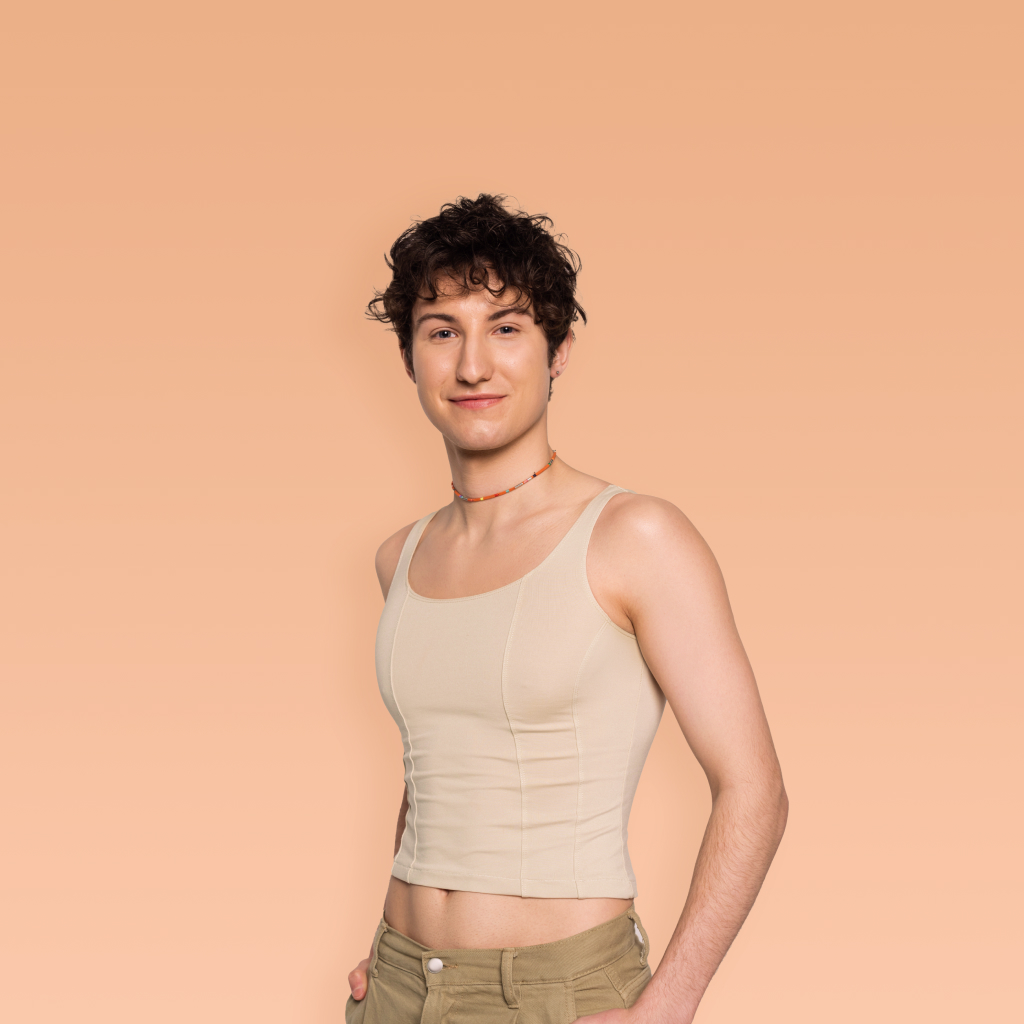 person wearing a beige camisole smiling on a peach background